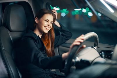 Happy young woman driving car at night