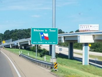 Information sign by road against sky