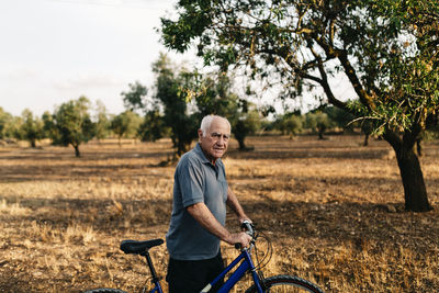 Senior man with bicycle on a field