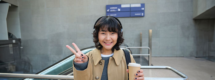 Portrait of young woman using mobile phone while standing in gym