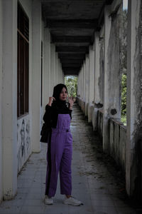 Full length portrait of woman standing against building