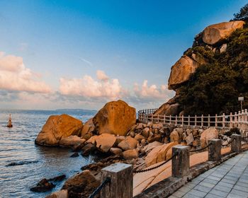 Rock formations by sea against blue sky