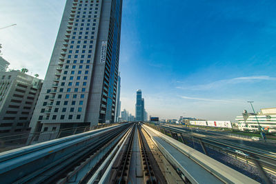 Railroad tracks amidst buildings in city against sky