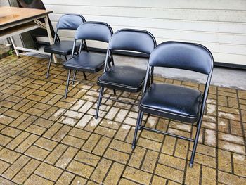 High angle view of empty chairs and table against tiled wall