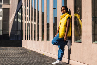 Portrait of woman standing against yellow wall