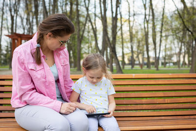 Side view of mother and daughter sitting at park