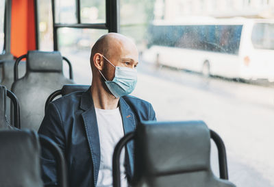 Man wearing mask while traveling in bus