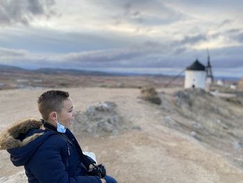 A child posing with his camera as he watches the views of the city of consuegra in toledo at dusk.