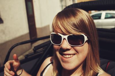 Portrait of smiling woman wearing sunglasses while sitting in car