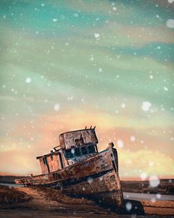 Abandoned boat against sky during sunset