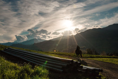 Person riding on horse by pipes on field against sky