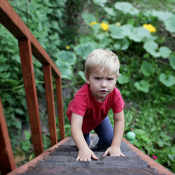 High angle portrait of boy climbing on ladder