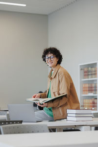 Side view of young woman using laptop while standing in office