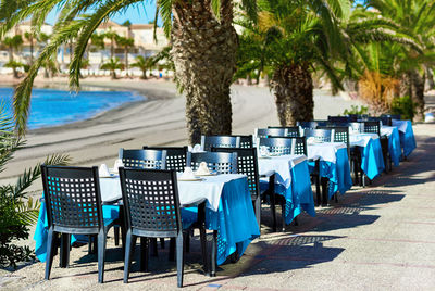 Empty chairs on beach against trees