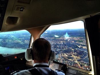 Rear view of pilot in airplane looking at city view through window