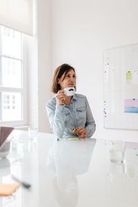 Businesswoman drinking coffee in meeting room at office