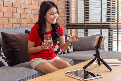 Young woman using phone while sitting on table