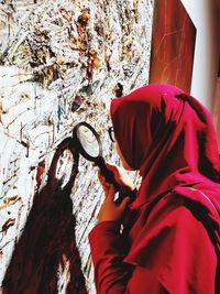 Side view of person standing against red wall