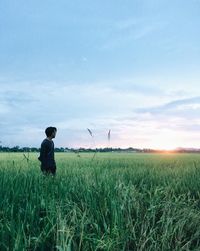 Rear view of man standing on field against sky