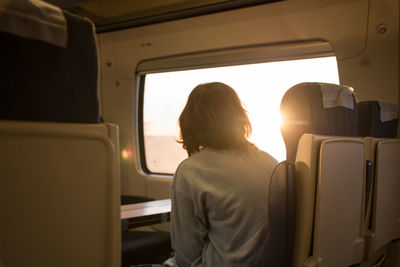 The traveling young girl looks dreamily from the window of the train into the sunrise