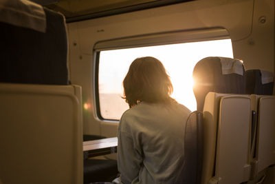 Rear view of woman looking through window