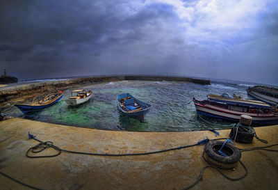 Boats in sea against cloudy sky