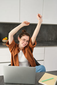 Portrait of young woman using mobile phone while sitting on table