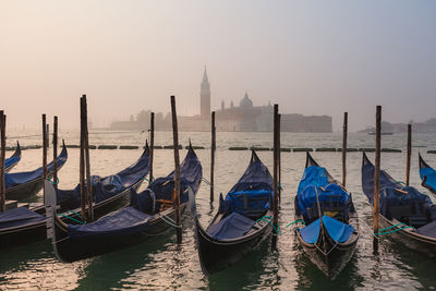 Gondolas on the pier. cathedral of san giorgio maggiore on the background. yearly foggy morning