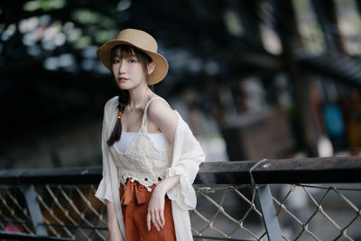 Portrait of young woman standing against trees