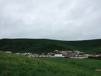 Scenic view of field and buildings against sky