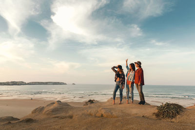 People standing at beach against sky