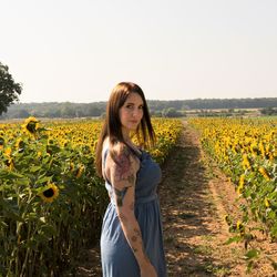 Portrait of woman standing on land amidst sunflowers