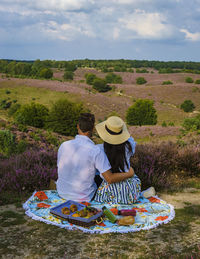 Rear view of woman sitting on field