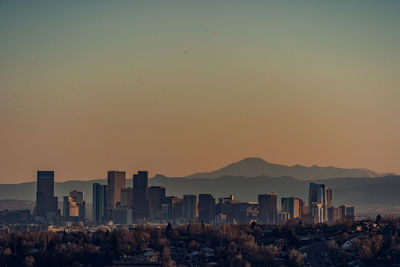 Buildings in city against clear sky during sunset