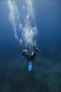 Friends diving around bubbles underwater