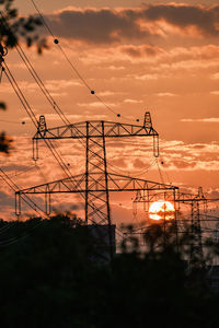 Low angle view of silhouette electricity pylon against sky during sunset