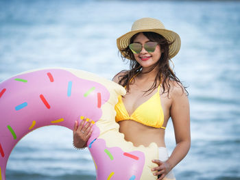 Portrait of woman with inflatable ring standing against sea