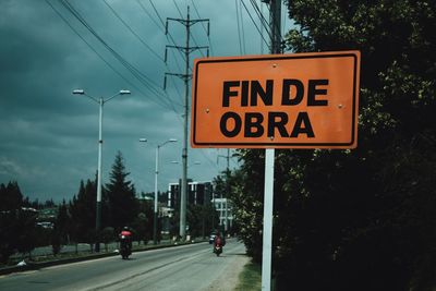 Information sign by road against sky