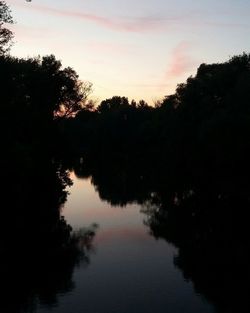 Reflection of silhouette trees in lake against sky during sunset