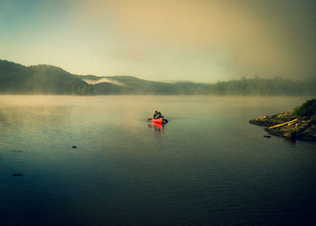 Scenic view of lake with people on canoe in morning 
