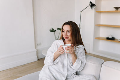 Young woman using mobile phone while sitting at home