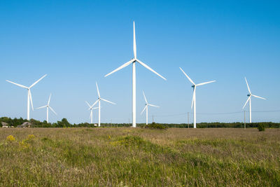 Wind turbines on field against blue sky