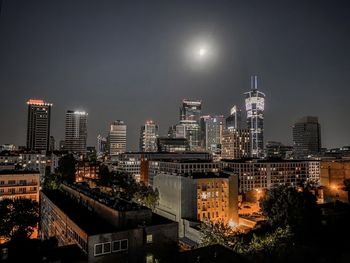 Illuminated buildings in city against sky at night