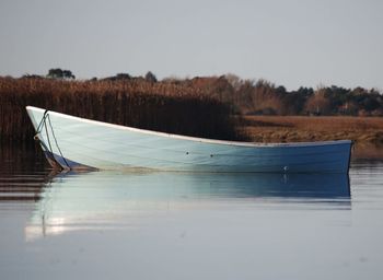 Sailboats moored on lake against sky