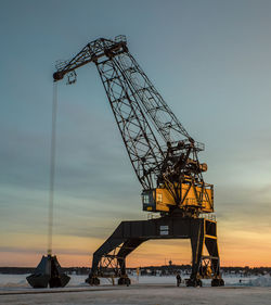 Low angle view of crane against sky at sunset