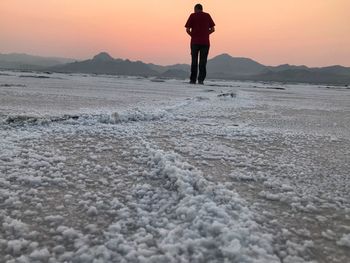 Rear view of man standing at bonneville salt flats during sunset