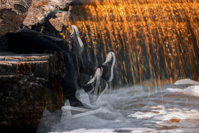 Multiple exposure of person sitting by waterfall