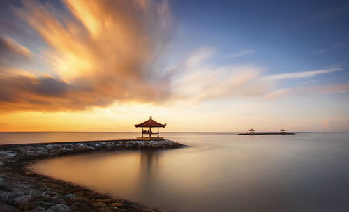 Scenic view of sea against cloudy sky during sunset