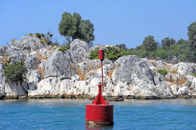 Red rock by sea against clear sky