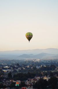 Hot air balloon flying over city against sky